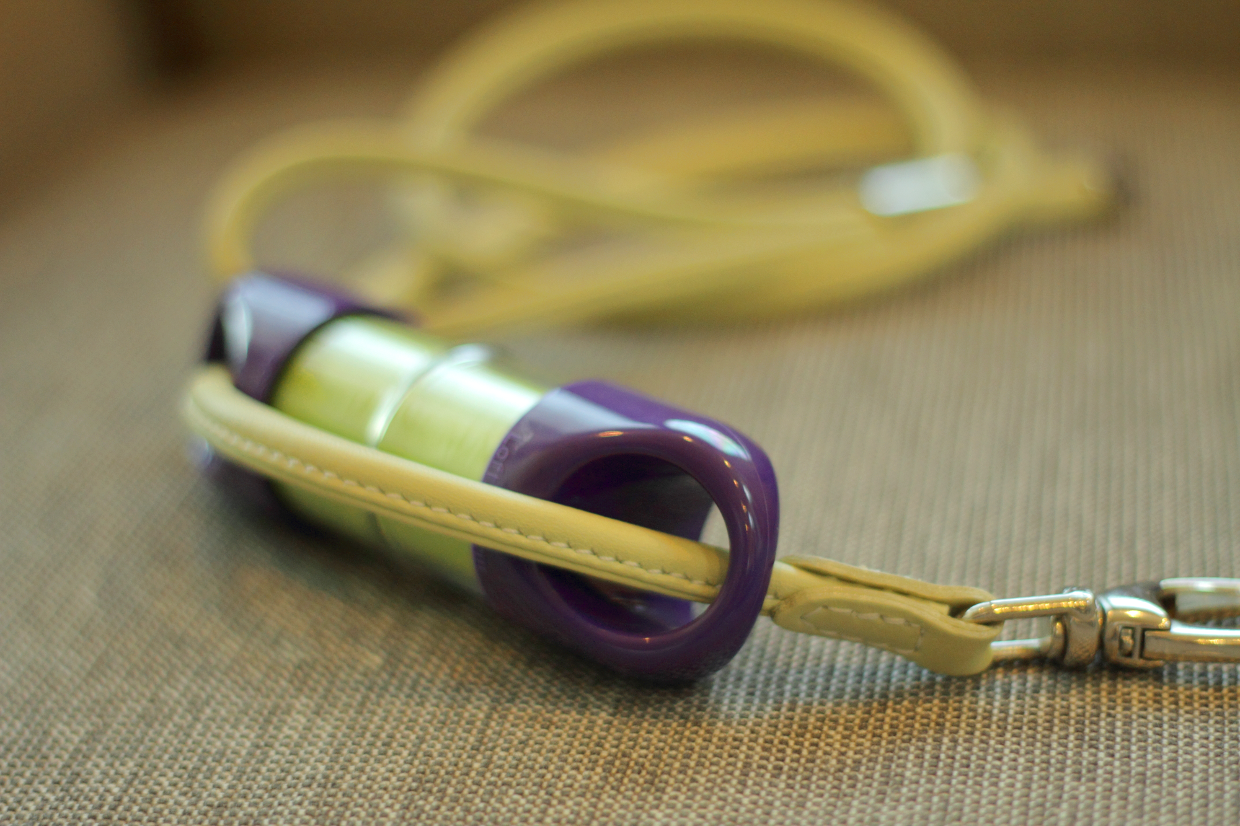Purple LOOP poop bag holder on a yellow leash on textured background.#color_purple
